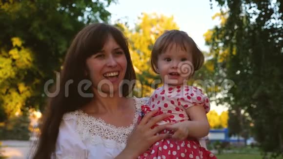 快乐的妈妈和女儿在炎热的夏天公园里捕捉大肥皂泡笑保姆和小女孩一起散步视频的预览图
