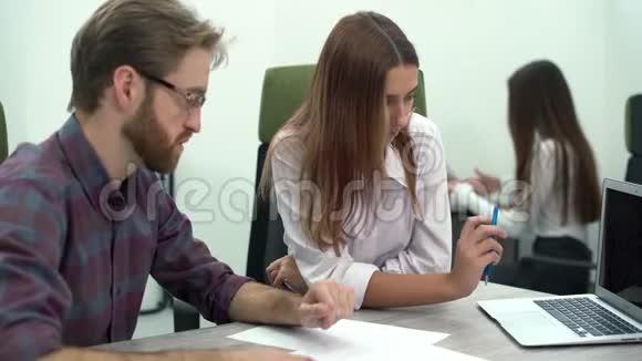 年轻的女人和男人在电脑上讨论一个项目他们打电话给他们的同事评论和帮助创意商业视频的预览图