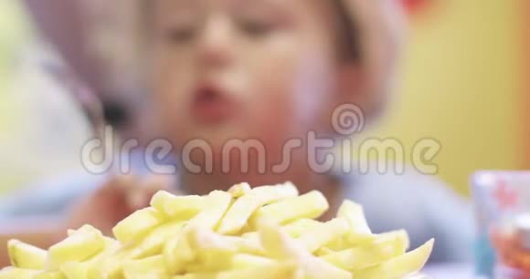 一个小男孩在咖啡馆里吃土豆薯条的肖像视频的预览图