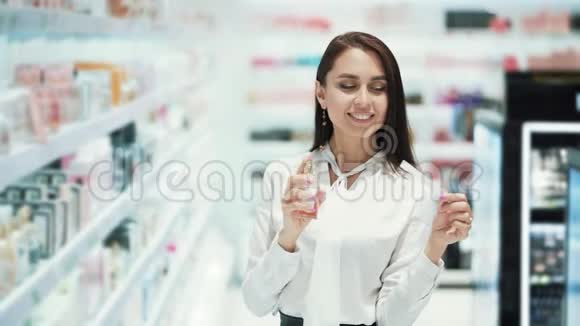 漂亮的女孩在化妆品店里选择香水喷在测试仪上慢动作视频的预览图