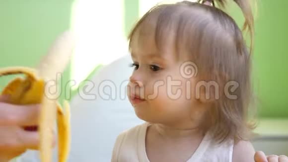 小宝宝吃香蕉女孩坐在餐桌旁的厨房里吃早餐视频的预览图