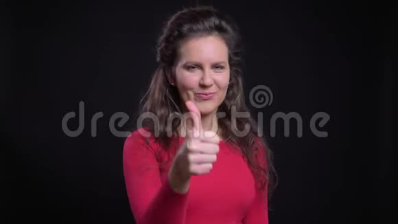 白种人女人戴着红色的肖像微笑着用手指示意在黑色镜头上表现出喜欢和尊重视频的预览图