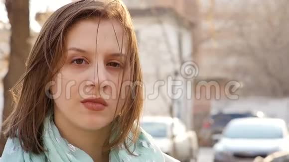 一位年轻女子站在风中的特写肖像春风吹着女孩头发慢动作视频的预览图