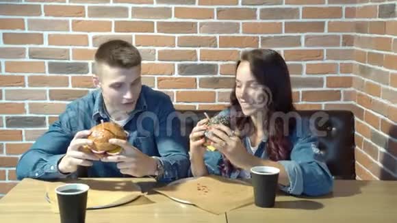在咖啡馆或餐馆吃汉堡的年轻情侣视频的预览图