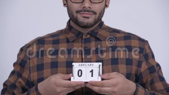 快乐的年轻留着胡子的印度嬉皮士拿着日历块准备新年视频的预览图