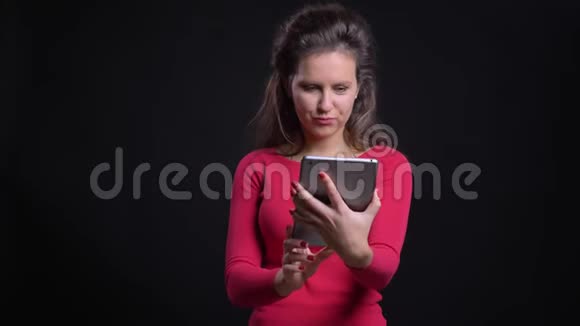 白种人女人在黑色背景下使用平板电脑在视频中微笑交谈的肖像视频的预览图
