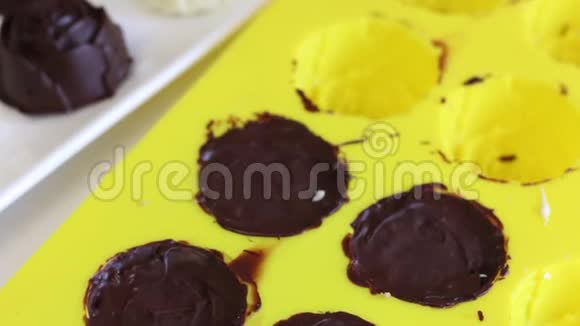 糖果白色和黑色巧克力釉加了碎杏仁躺在白色的盘子上在硅胶形状附近准备视频的预览图
