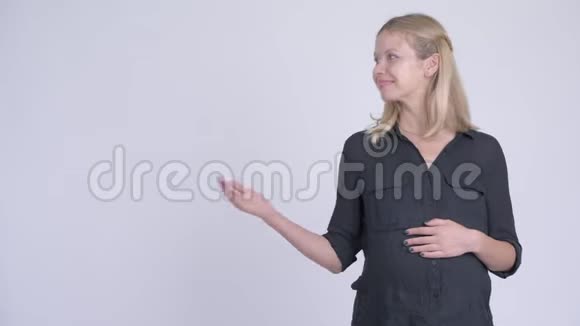 年轻快乐的怀孕女商人一边说话一边展示视频的预览图