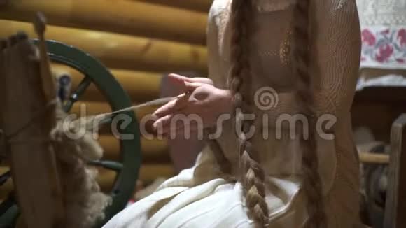 有长发的女人在老式木屋内部纺羊毛视频的预览图