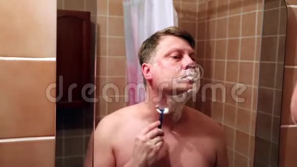 一个男人在镜子前剃掉脸颊下巴和脖子视频的预览图