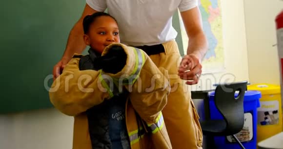 男消防员帮助非裔美国女孩在教室里穿消防制服小女生斯密视频的预览图