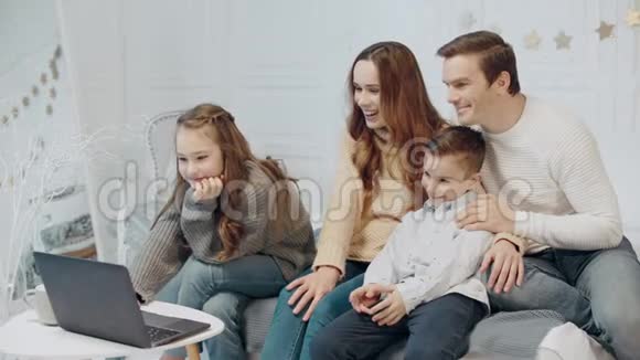 微笑的家人一起在客厅的笔记本电脑上看视频视频的预览图