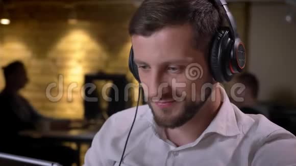 年轻开朗的白种人商人用耳机听音乐用平板电脑的特写肖像视频的预览图