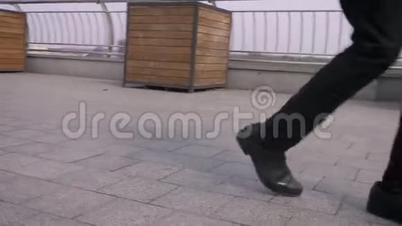 男性腿部做惊人的步法和在城市户外街道上跳舞的特写镜头视频的预览图