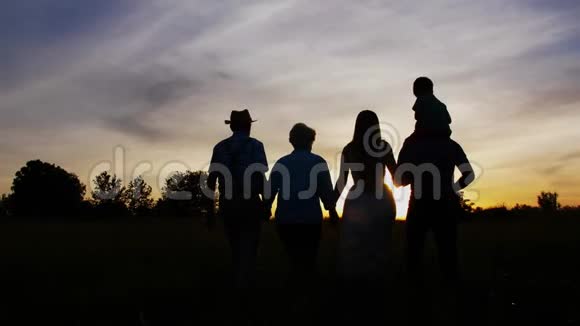日落时分三代一家人在草地上散步视频的预览图