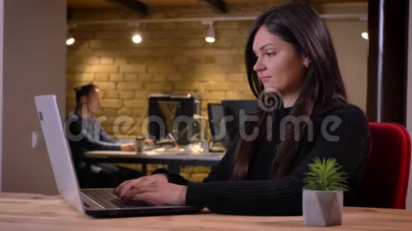 中年黑发女商人在办公室工作时用笔记本电脑打字的特写照片视频的预览图