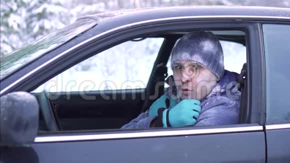 一个冻僵的人坐在车里从寒冷中发抖视频的预览图