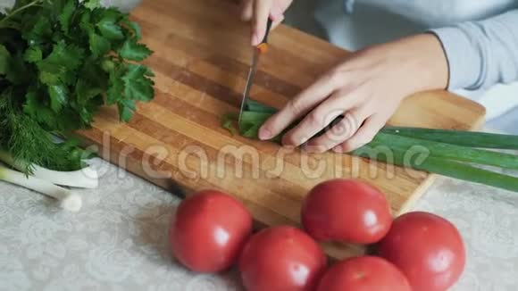 女人用刀在木板上切青葱的手特写健康食品视频的预览图