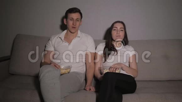 一对夫妇喜欢在家里看电影在沙发上笑视频的预览图