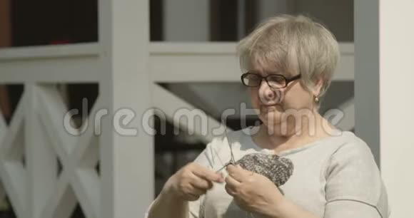 戴红相机拍摄的护理院穿着针织老年妇女坐在室外微笑的快乐退休视频的预览图