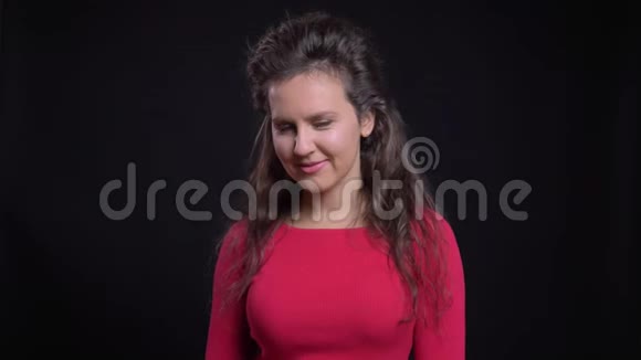 白种人女人的肖像在黑色背景下带着调情的微笑进入镜头视频的预览图