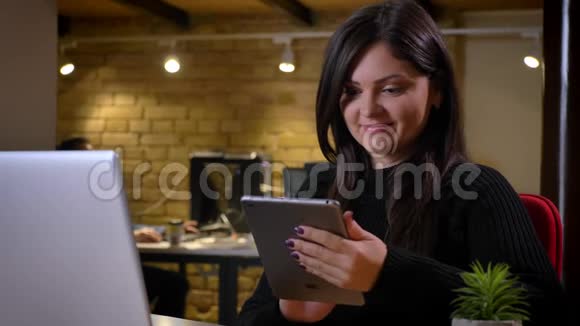 白种人成年女商人的特写肖像她在平板电脑上滚动着网络坐在面前微笑视频的预览图