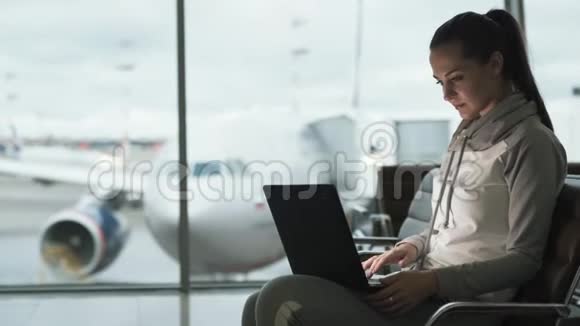 女旅行者运动服装自由职业者使用笔记本电脑在机场休息室工作视频的预览图