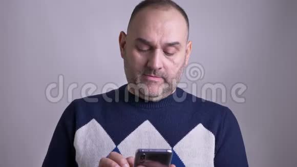 中年白种人男性的特写镜头在电话上发短信带着孤立的背景微笑视频的预览图