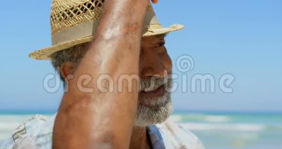 积极的非裔美国人戴着帽子站在阳光下海滩的正面景色视频的预览图