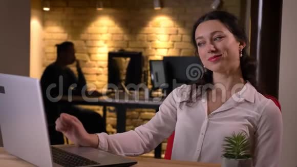 满意的年轻白种人女办公室职员在笔记本电脑上微笑着坐着的特写照片视频的预览图