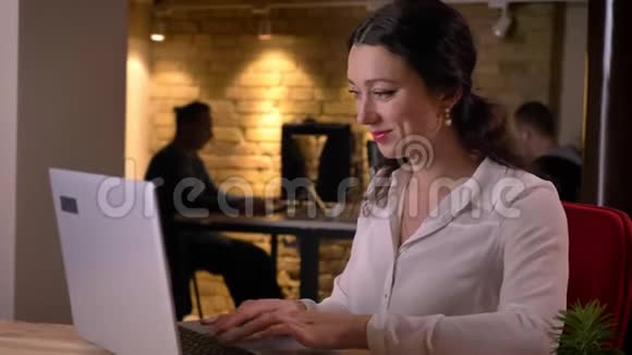 可爱的年轻白种人女办公室工作人员在笔记本电脑上的特写肖像微笑着傻笑视频的预览图