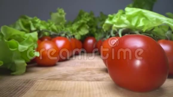 多利的红喜花西红柿与生菜叶上的木制桌子背景滑过自家种植的蔬菜视频的预览图
