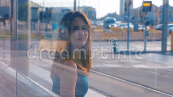 年轻迷人的女人坐在公共汽车或地铁车站两次曝光女孩在等她的电车城市生活方式视频的预览图