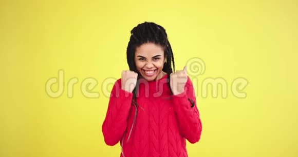 可爱的非洲女士在一个工作室与黄色背景墙微笑的镜头前和跳舞视频的预览图