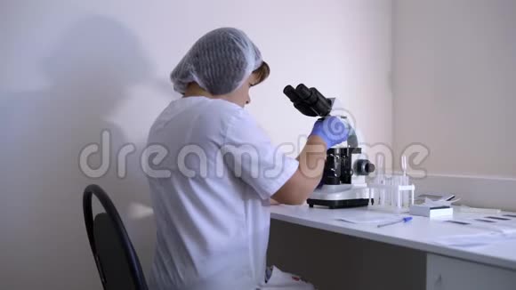 实验室的女科学家在显微镜下进行研究视频的预览图