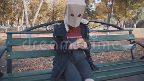 那个头上戴着包裹的女孩正坐在一张带着奶酪汉堡的长凳上穿夹克的女孩视频的预览图