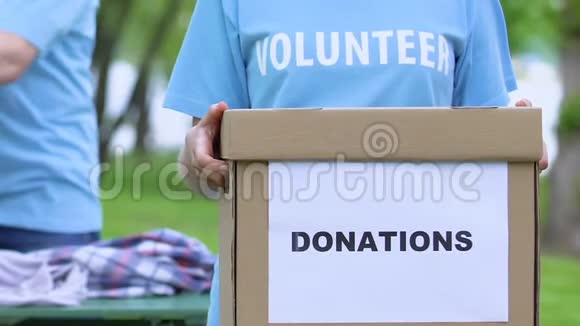 女志愿者手持捐款箱人们整理衣物人道主义援助视频的预览图