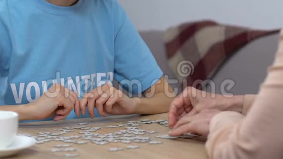 青年志愿者和老年妇女在养老院做拼图游戏休闲活动视频的预览图