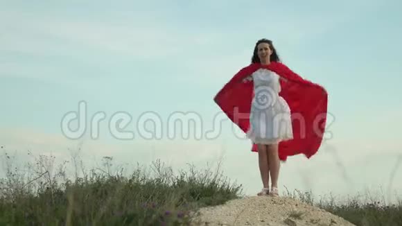 有趣又有趣的女人穿着红色斗篷扮演英雄女孩梦想成为超级英雄美丽的超级英雄女孩视频的预览图