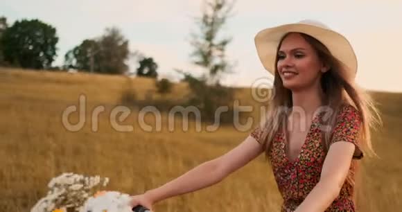 中间的计划是戴着帽子的金发女郎骑着一辆带着鲜花和微笑的自行车视频的预览图