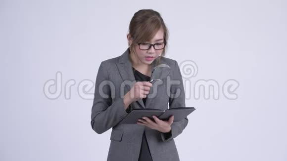 年轻的亚洲女商人用放大镜看书视频的预览图