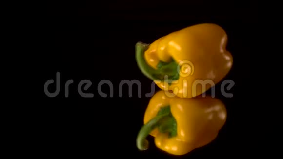 新鲜的黄椒落在黑桌上在黑镜桌上分离或爆炸黑色背景视频的预览图