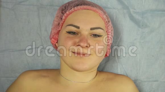 一个微笑的女人躺在医疗沙发上的脸视频的预览图