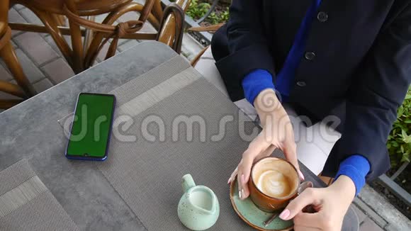 年轻迷人的商务女性在咖啡厅使用绿色屏幕的手机侍者端来一个芝士蛋糕一杯视频的预览图