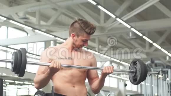 在健身房用杠铃锻炼肌肉的年轻人视频的预览图
