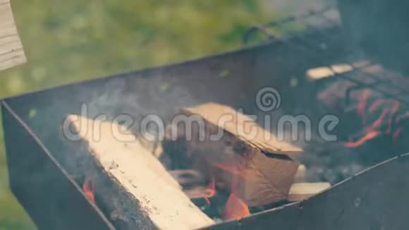 男人在烤架里扔几根木头点燃小火下午在街上视频的预览图