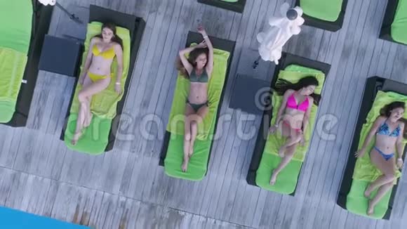 避暑胜地迷人的快乐女性朋友穿上泳衣在昂贵的度假胜地游泳池附近的躺椅上放松视频的预览图