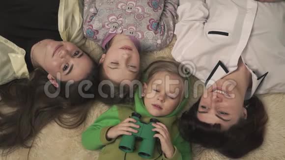 幸福的一家人躺在蓬松的地毯上微笑着妈妈和孩子们都很开心穿着睡衣的滑稽小男孩视频的预览图