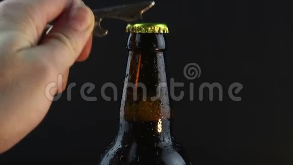 酒保打开一瓶雾蒙蒙的黑啤酒一个年轻人的手打开一瓶又冷又黑的啤酒视频的预览图