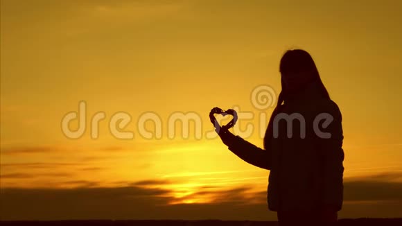 少女站在夕阳下手里握着心视频的预览图